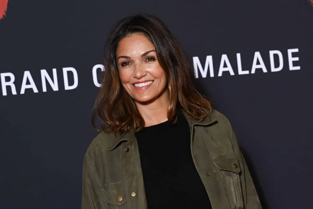 Nadia Farès souriante lors d'un événement cinéma, veste kaki et haut noir