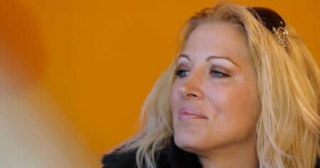 Loana en gros plan, regard pensif, cheveux blonds, fond orange