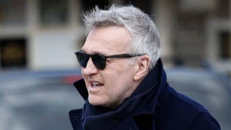 Laurent Ruquier en lunettes noires et écharpe marine, regard de côté