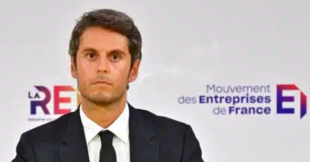 Gabriel Attal lors d'une prise de parole publique devant le logo du Mouvement des Entreprises de France