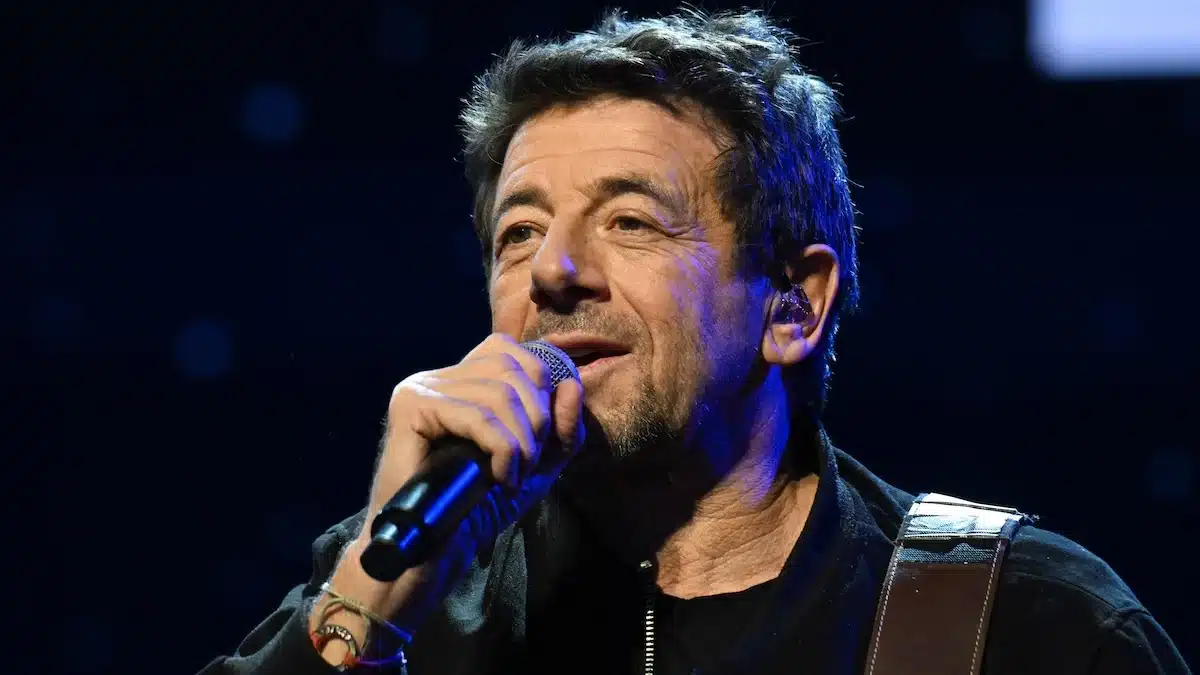 Patrick Bruel chantant au micro sur scène lors d'un concert