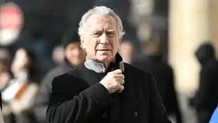 William Leymergie en manteau noir dans la rue, regard sérieux