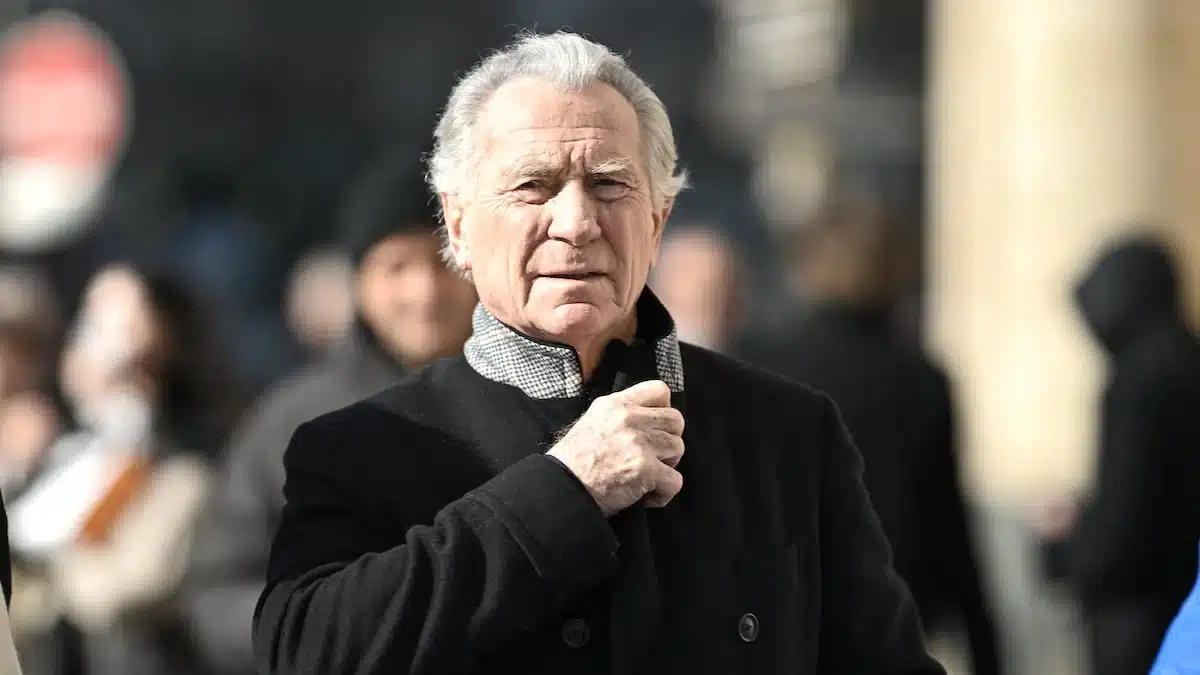 William Leymergie en manteau noir dans la rue, regard sérieux