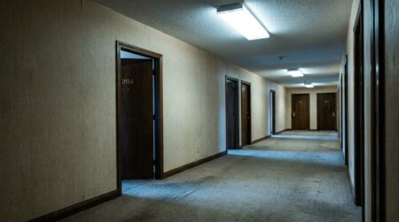 Couloir d'hôtel vide faiblement éclairé avec portes numérotées