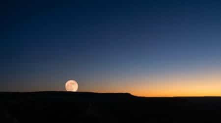 Pleine lune se levant au-dessus de l'horizon au crépuscule