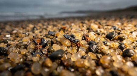 Gros plan sur des grains de sable mêlés à des éclats métalliques oxydés