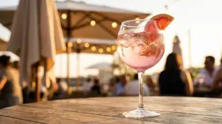 Verre ballon de spritz rosé avec glaçons et pamplemousse en terrasse