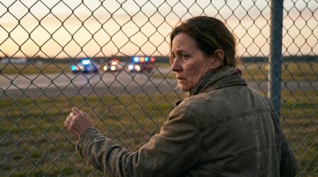 Femme de dos agrippée à une clôture d'aérodrome en état de choc