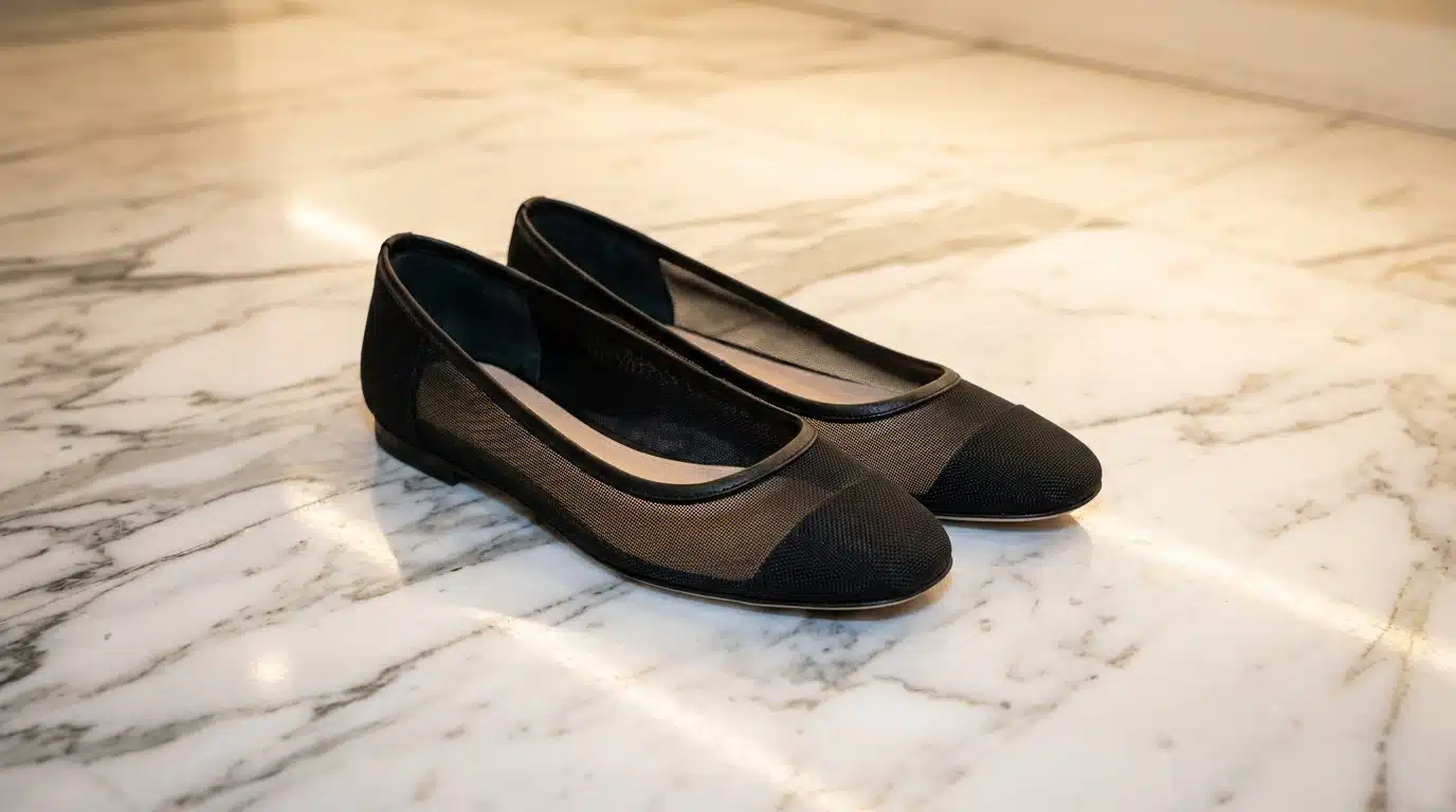 Ballerines noires en résille posées sur un sol en marbre