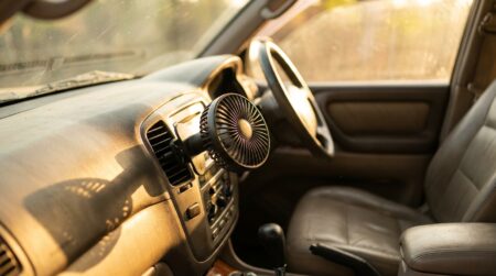 Petit ventilateur USB noir fixé sur une grille d'aération de voiture