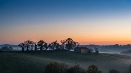 Ciel d'avant l'aube avec traînées de météores au-dessus de la campagne