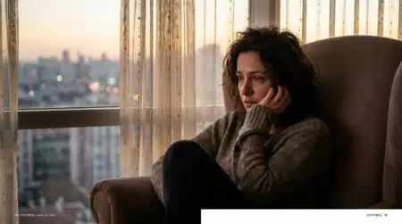 Femme pensive assise près d'une fenêtre au crépuscule