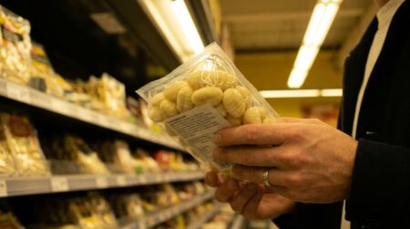 Paquet de gnocchis tenu en main dans un rayon de supermarché