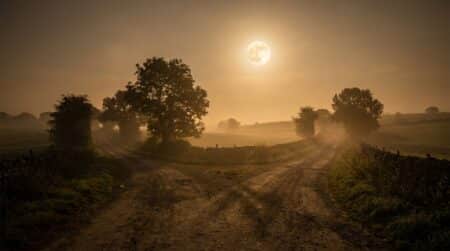 Pleine lune au-dessus d'un carrefour de chemins en campagne