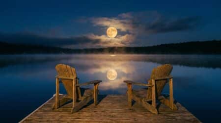 Pleine lune reflétée sur un lac avec deux chaises vides