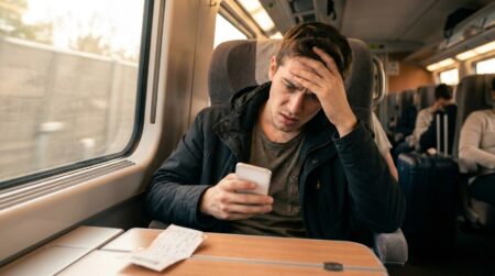 Jeune homme incrédule regardant son téléphone dans un TGV