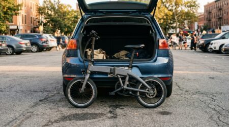 Vélo électrique pliable garé près d'un coffre de voiture