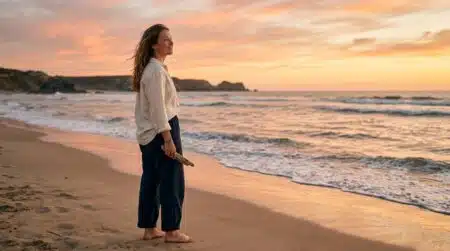 Jeune femme souriante face au coucher de soleil sur la plage