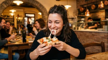 Femme souriante mangeant une part de pizza fondante
