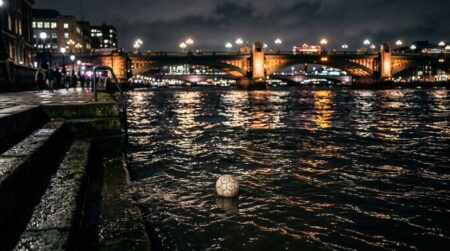 Ballon de foot flottant seul sur le Rhône de nuit