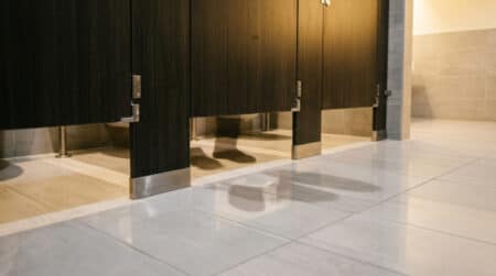 Espace visible sous une porte de toilettes publiques
