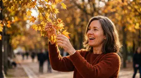 Femme émerveillée devant des feuilles d'automne dorées