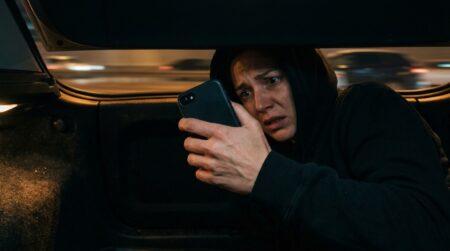 Femme apeurée tenant un téléphone dans un coffre