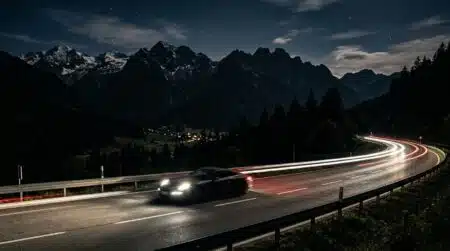 Voiture de sport filant de nuit sur une autoroute alpine