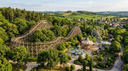 Montagnes russes en bois dans un parc entouré d'arbres