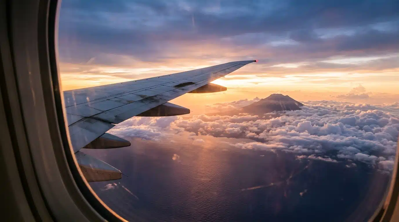 Aile d'avion au lever du soleil au-dessus d'une île volcanique
