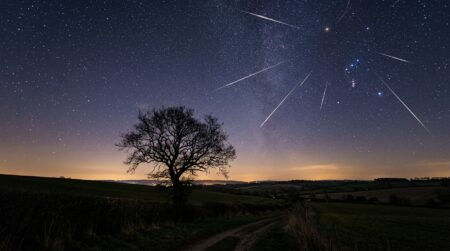 Étoiles filantes traversant un ciel nocturne au-dessus d'une campagne