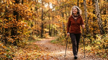 Femme sénior souriante en marche nordique en forêt