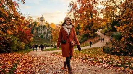 Promeneuse sur un sentier de feuilles rouges aux Buttes-Chaumont